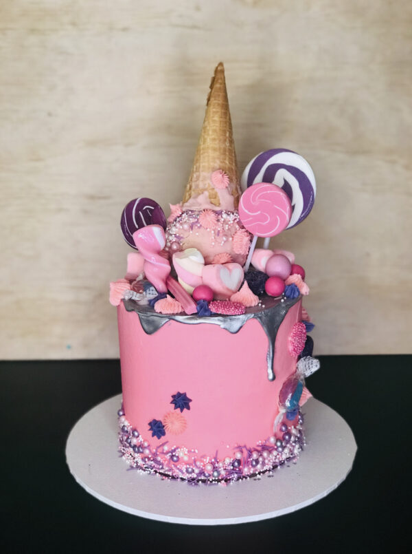 Pink cake with candy and ice cream cone